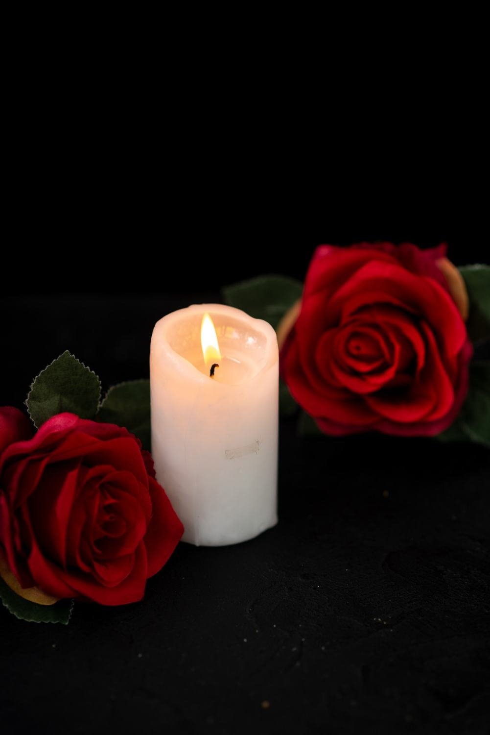 Front view of little grave with candle and red roses on black
